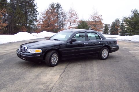 2001 Ford Crown Victoria - A black 2001 Ford Crown Victoria sedan is viewed from the front three-quarter angle on a cloudy day.