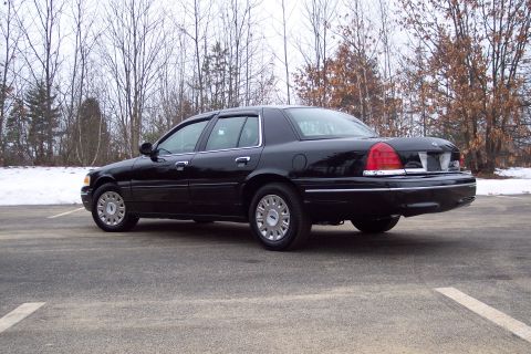 2001 Ford Crown Victoria - This black 2001 Ford Crown Victoria is shown from a rear three-quarter angle in a parking lot with bare trees and snow.