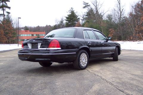 2001 Ford Crown Victoria - A black 2001 Ford Crown Victoria is viewed from the rear quarter angle on a cloudy day.