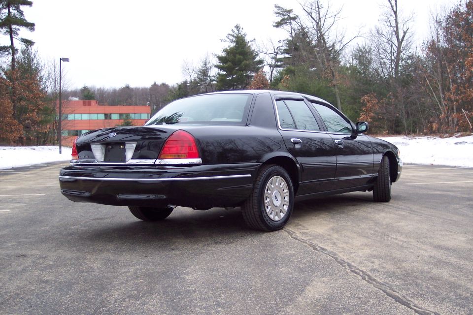 Black 2001 Ford Crown Victoria rear quarter view, parked on asphalt with snow in background