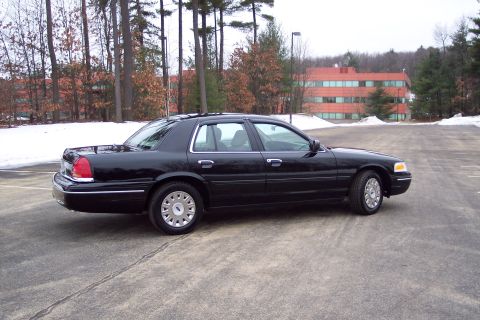 2001 Ford Crown Victoria - Side view of a black 2001 Ford Crown Victoria sedan parked in a lot with snow on the ground.