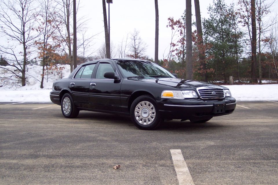 Black 2001 Ford Crown Victoria parked on asphalt with snow in the background