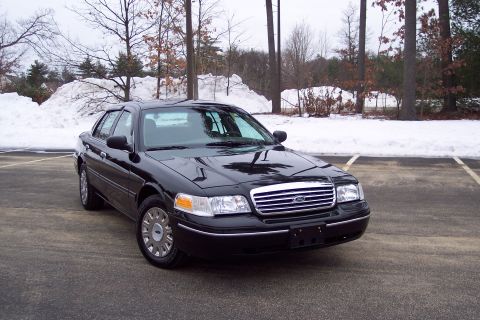 2001 Ford Crown Victoria - A black 2001 Ford Crown Victoria is parked in a lot with snow in the background.