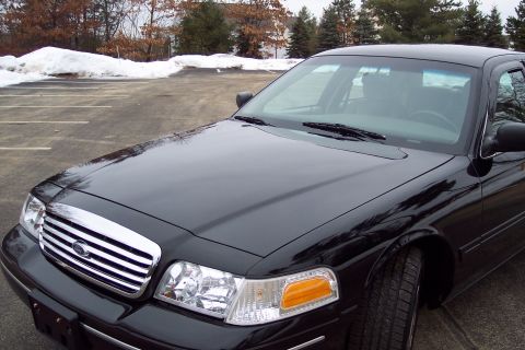 2001 Ford Crown Victoria - Front view of a black 2001 Ford Crown Victoria parked in a lot with snow in the background.