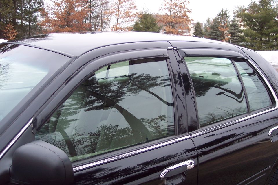 side view of a black sedan with chrome door handles and window visors
