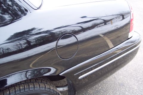 2001 Ford Crown Victoria - Rear quarter panel of a black 2001 Ford Crown Victoria, showing the fuel door and chrome trim details.