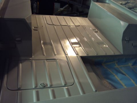 1948 Jeep Wrangler - The interior floor of a vehicle shows a ribbed metal surface with access panels and a blue tarp in the background.
