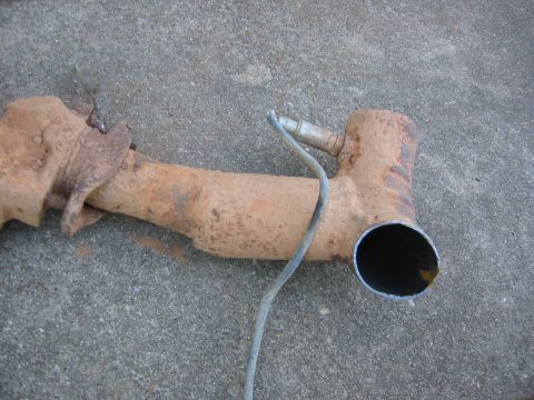 1995 Ford Bronco - This is a rusted exhaust pipe with an oxygen sensor attached, shown on a concrete surface.