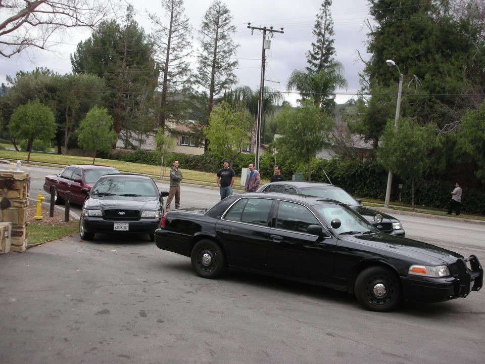 Black Ford Crown Victoria police car with push bumper, angled from the front right