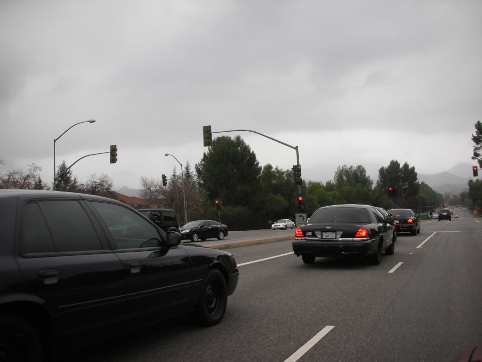 Black Crown Victoria police car driving on a road, another Crown Victoria behind it