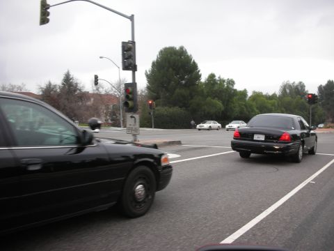 1992 Ford Crown Victoria - Two black sedans and two white cars at a traffic light intersection on an overcast day.