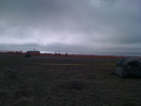 1989 Ford Bronco - A tent is set up on a beach with the ocean and cloudy sky visible.