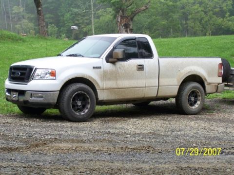2004 Ford F-150 - A white 2004 Ford F-150 pickup truck is parked on a gravel road in a rural setting.