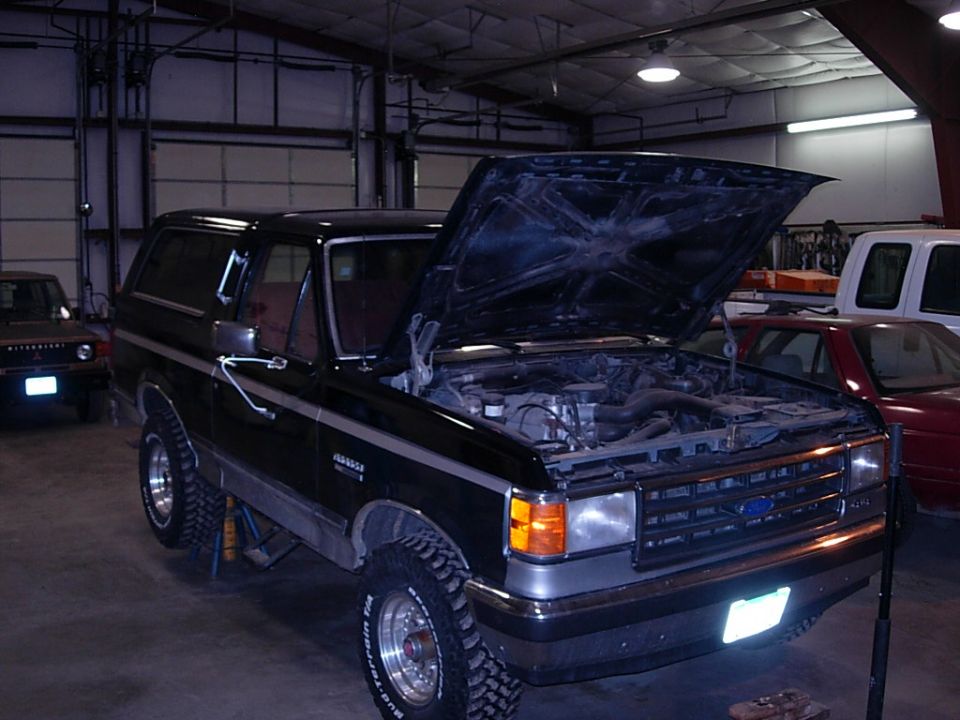 1989 Ford Bronco with hood open in garage, another vehicle in background