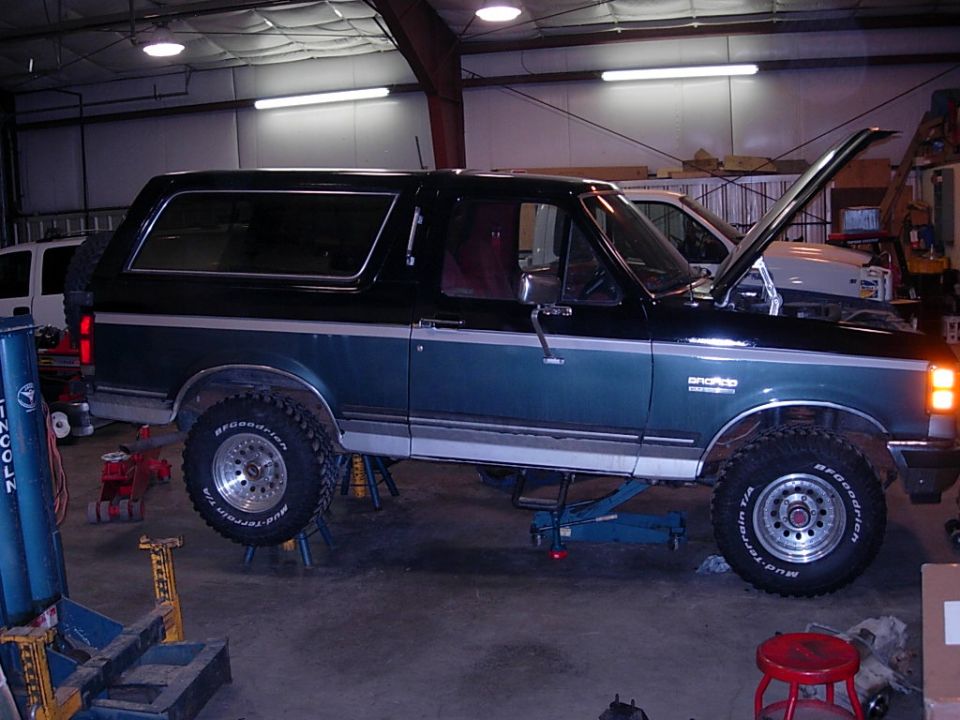 1989 Ford Bronco in garage with hood up, on jack stands