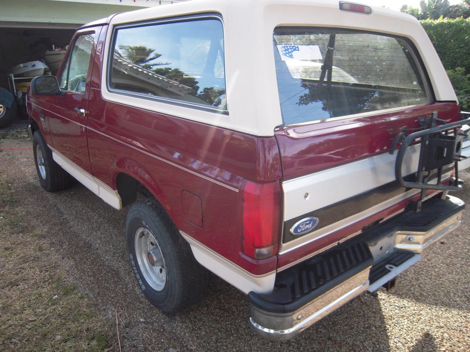 Rear three-quarter view of a red Ford Bronco with tan top