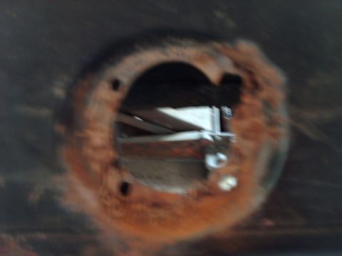 1978 Ford Mustang II - A close-up view of a rusted hole on the underside of a vehicle, revealing internal structural components.