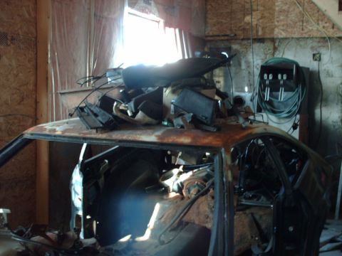 1978 Ford Mustang II - A heavily rusted car body, stripped of many components and filled with debris, sits in a workshop.