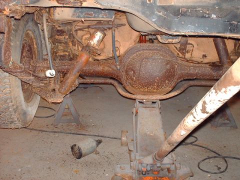 1978 Ford Mustang II - Undercarriage view of a heavily rusted vehicle's rear axle and suspension components.