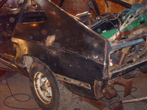 1978 Ford Mustang II - Rear quarter panel of a black car shows significant rust and damage, indicating it is in a state of disrepair.