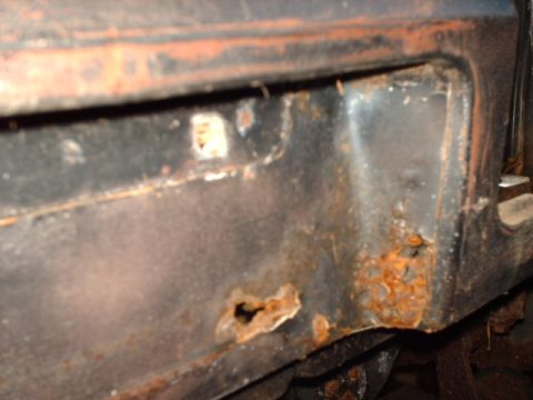 1978 Ford Mustang II - Corrosion and rust holes are visible on this metal car part.