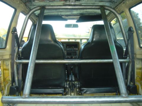 1983 Volkswagen Rabbit - The interior of a car is shown with a prominent roll cage and black bucket seats.