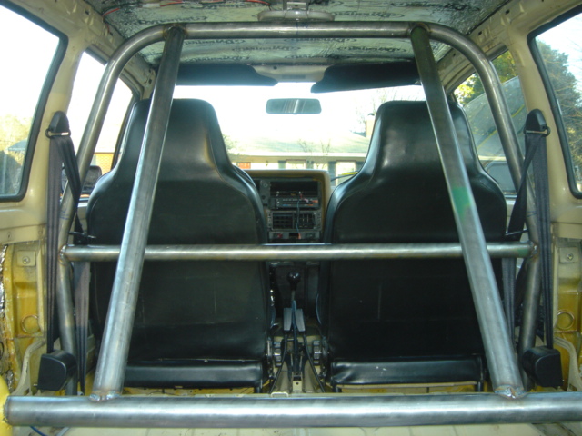Car interior with roll cage, black bucket seats, and dashboard visible