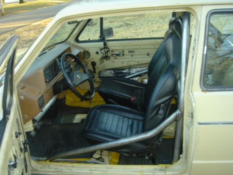 1983 Volkswagen Rabbit - The interior of a car is visible, a roll cage and black seats. The registry claims it is a 1983 Volkswagen Rabbit, but this cannot be confi…