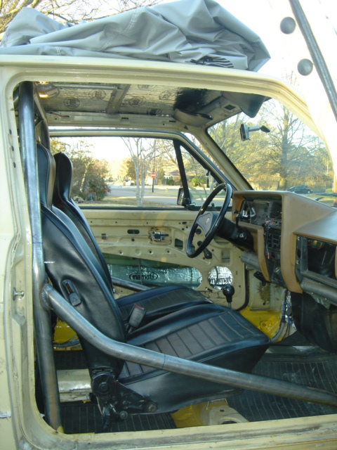 1983 Volkswagen Rabbit - Car interior modified with a roll cage and racing seats, showing sound dampening on the ceiling and doors.