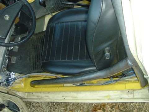 1983 Volkswagen Rabbit - Interior view of a car showing a black seat and a metal roll cage bar installed near the floor.