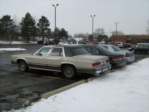 1988 Mercury Grand Marquis - A 1988 Mercury Grand Marquis is seen parked in a lot with snow on the ground, alongside other vehicles.
