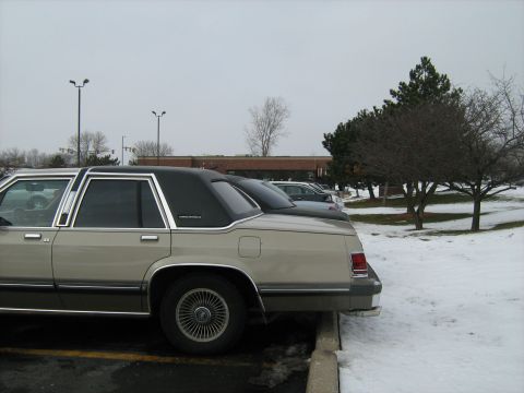 1988 Mercury Grand Marquis - A 1988 Mercury Grand Marquis is parked next to another car in a snowy parking lot.