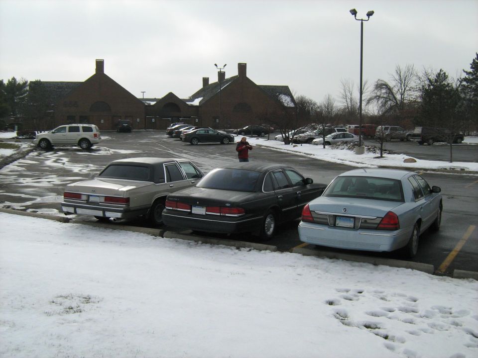 Silver sedan rear view, parked in snow. Likely a 1998-2002 Mercury Grand Marquis