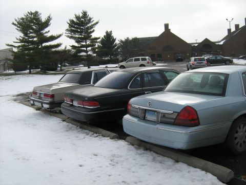 1988 Mercury Grand Marquis - Three sedans are parked in a lot covered with snow.