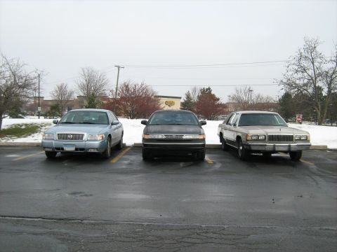 1988 Mercury Grand Marquis - A 1988 Mercury Grand Marquis is parked in a lot alongside two other sedans on a cloudy day.
