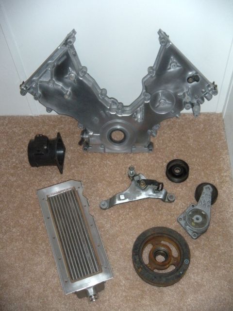 1992 Ford Bronco - Various engine components including a timing cover and oil cooler are displayed on a carpeted surface.
