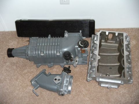 1992 Ford Bronco - These engine parts are laid out on a carpeted floor, possibly for sale or installation.