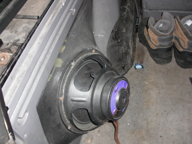 Speaker mounted in car interior panel, with boots visible in background