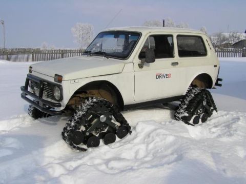 1987 Suzuki Samurai - Off-road vehicle equipped with snow tracks navigates a snow-covered terrain.