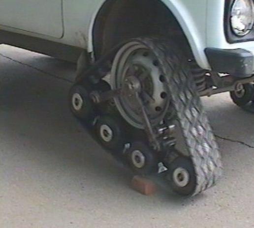 Exposed hub of white SUV fitted with a diamond-plate track roller conversion unit.