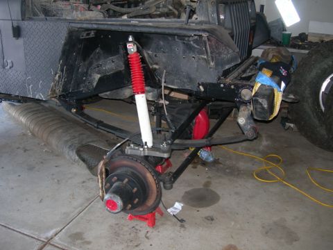 1991 Jeep Wrangler - A Jeep Wrangler's front suspension is shown during a modification, a red shock absorber and a large tire.