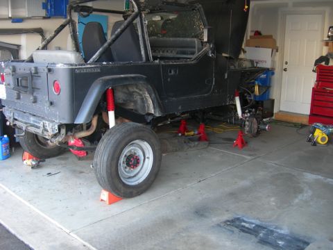 1991 Jeep Wrangler - This 1991 Jeep Wrangler is up on jack stands in a garage, indicating it's being worked on.