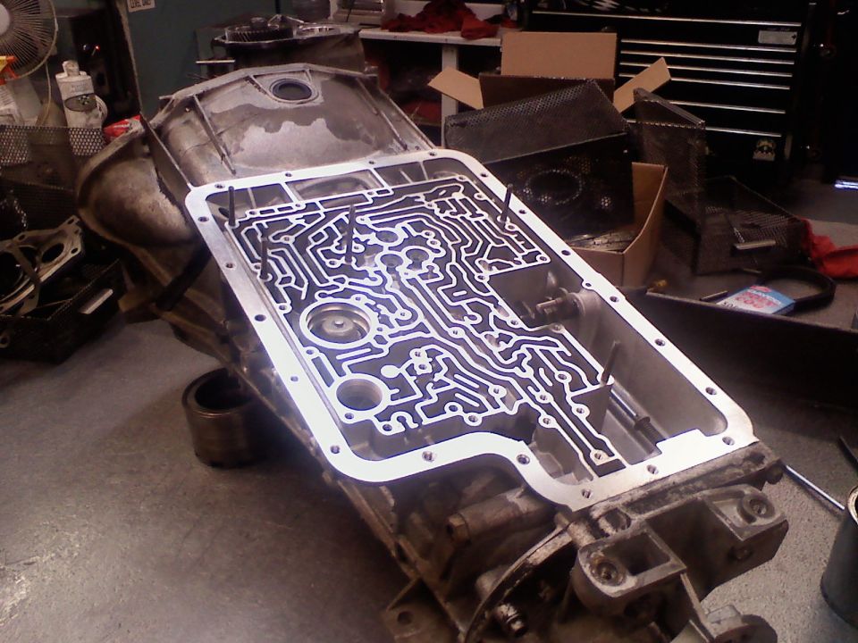 Inverted automatic transmission with pan removed showing valve body passages in a garage