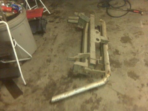 1992 Ford F-350 - A detached truck bumper and exhaust pipe are on the floor next to a trash can and chairs.