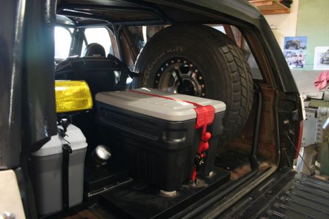 1986 Ford Bronco - Cooler and spare tire stored inside a vehicle's cargo area.