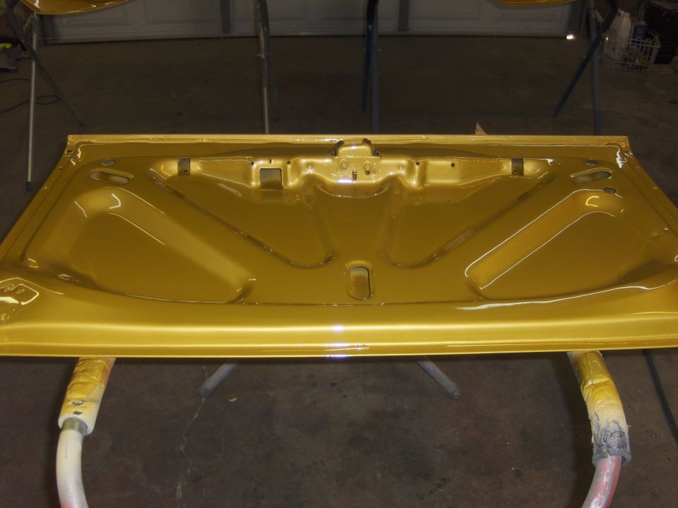 Gold painted car hood underside with bracing and latch mechanism, resting on sawhorses