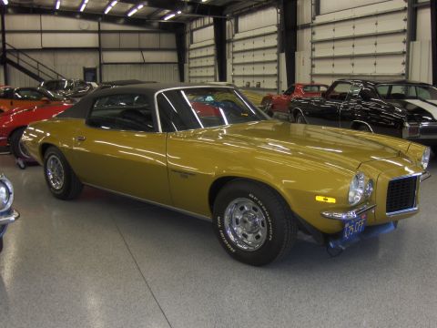 1971 Chevrolet Camaro - A gold 1970 Chevrolet Camaro is parked inside a garage with other vehicles visible in the background.