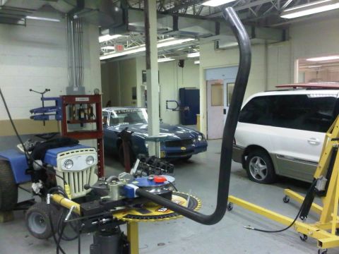 1996 Ford Bronco - Workshop interior shows multiple vehicles and machinery, including a blue car and white van.