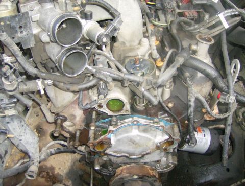 1994 Ford Bronco - Close-up view of an engine bay, focusing on the water pump area and an oil filter. Text from Supermotors.net is visible at the bottom.