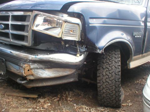 1993 Ford Bronco - Front view of a damaged 1993 Ford Bronco, showing collision damage to the headlight and bumper area.